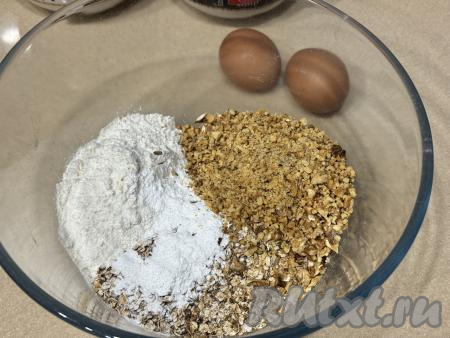 В глубокой миске соединить обжаренные хлопья, муку, соль и разрыхлитель. Ядра грецких орехов измельчить ножом достаточно мелко и тоже добавить в миску, перемешать получившуюся овсяно-ореховую смесь.