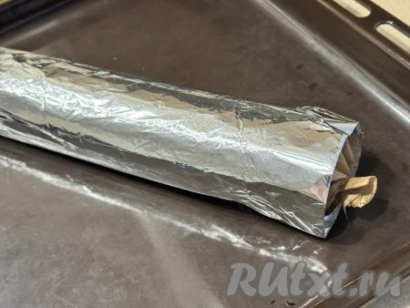 Рулет завернуть в пергамент, закрывая рулет, как конфету, со всех сторон, а затем ещё и в лист фольги. Переложить рулет на противень.