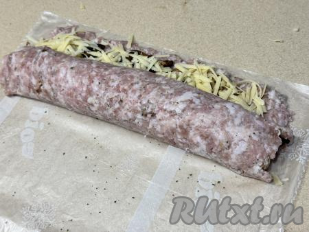 Начиная с узкой стороны прямоугольника, помогая целлофановым пакетом, свернуть фарш с начинкой из шампиньонов и сыра в плотный рулет.&nbsp;