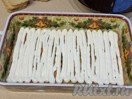 Отсадить ровным слоем часть крема поверх печенья. Если у вас нет кулинарного мешка, можно выкладывать и равномерно распределять крем столовой ложкой.