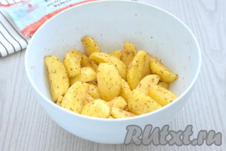 Тщательно перемешиваем дольки картофеля, покрывая их специями со всех сторон.