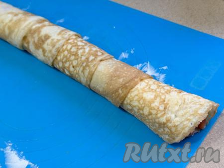 Свернуть блинчики с начинкой в плотный рулет, начиная с широкой стороны пласта из яичных блинов.&nbsp;