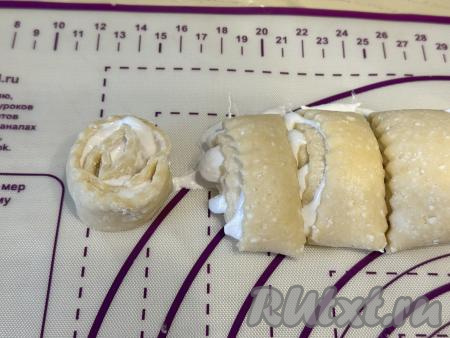 Творожное тесто, покрытое взбитыми белками, свернуть в рулет, начиная с более длинной стороны пласта. Нарезать получившийся рулет на кусочки толщиной примерно&nbsp;2,5 сантиметра.&nbsp;