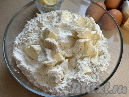 Прежде всего замесим творожное тесто для печенья. Для этого из холодильника нужно достать сливочное масло, нарезать его на кусочки. В глубокую миску всыпать 350 грамм просеянной муки, ванильный сахар, добавить кусочки холодного масла, размять руками до получения крошки.&nbsp;
