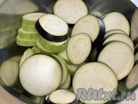 Вымытый баклажан нарезать на кружочки толщиной также около 1,5 сантиметров, добавить в миску с кабачками.