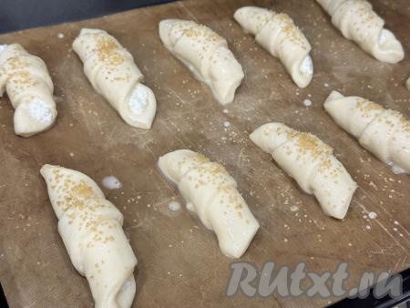 Оставить рогалики для расстойки на 20 минут. В небольшой ёмкости взбить вилкой яичный желток. После расстойки смазать рогалики взбитым желтком и, по желанию, присыпать их сахаром (я присыпала коричневым сахаром).&nbsp;У меня все рогалики не поместились на один противень, поэтому я выпекала их в духовке в несколько заходов.