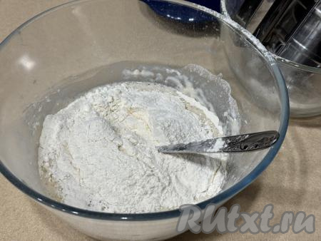 В миску с получившейся смесью всыпать 250 грамм муки, перемешать дрожжевое тесто для рогаликов столовой ложкой. Постепенно добавляя в миску оставшуюся просеянную муку и тщательно вмешивая её, вначале перемешивать тесто ложкой. А как только дрожжевое тесто начнёт собираться в ком, продолжать замешивать его руками, всыпая оставшуюся просеянную муку только по мере необходимости.