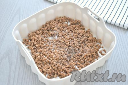 Промытую гречневую крупу выкладываем в силиконовую форму, по вкусу солим, перчим, перемешиваем.