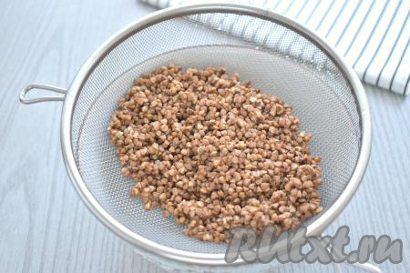 Гречневую крупу при необходимости перебираем, удаляя чёрные зёрнышки. Перекладываем гречку в сито и хорошо промываем под проточной водой, даём стечь лишней воде.