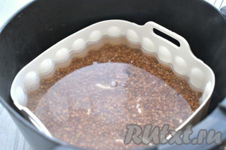 Форму с гречкой ставим в чашу аэрогриля, вливаем 350 миллилитров воды комнатной температуры. Отправляем чашу в аэрогриль. Выставляем температуру аэрогриля 190 градусов, а время - 15 минут. После 7-8 минут с начала приготовления достаём чашу из аэрогриля, гречку перемешиваем и снова отправляем в аэрогриль.