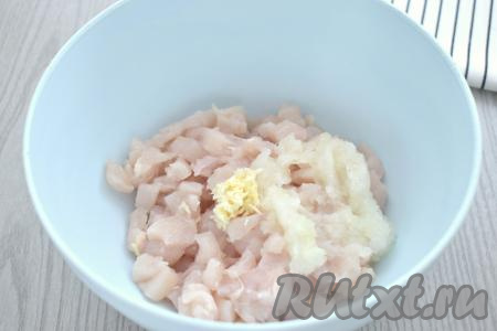 Лук и чеснок очищаем, натираем на мелкой тёрке, выкладываем в миску с нарезанным куриным мясом.