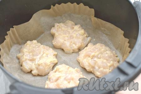 Чашу аэрогриля застилаем пергаментом. Слегка смазываем пергамент растительным маслом. На пергамент выкладываем примерно по 1,5 столовых ложки куриной массы в виде круглых котлет. В чашу аэрогриля у меня поместились 4 рубленных котлеты, поэтому я готовила котлеты в аэрогриле в несколько заходов. Отправляем чашу с котлетами в аэрогриль.