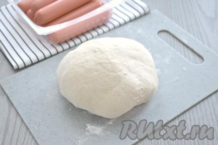 Вначале перемешиваем тесто лопаткой (или столовой ложкой). Когда тесто соберётся в комок, продолжаем замешивать его руками, подливая по мере необходимости оставшуюся воду, обязательно учитывая, что дрожжевое тесто должно получиться мягким, не липнущим к ладоням. Как только добились нужной консистенции теста, значит больше воду добавлять не нужно. Вымешивать тесто руками в общей сложности нужно не менее 7 минут. Накрываем миску с тестом полотенцем и оставляем в тёплом месте на 1 час (до увеличения теста в объёме раза в 2-3).