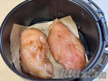 Дно чаши аэрогриля застелить куском пергаментной бумаги, выложить куриную грудку, замаринованную в соевом соусе. Отправить чашу в аэрогриль.