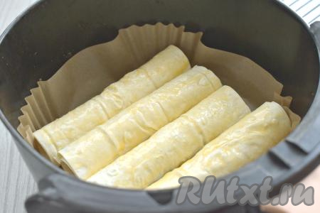 В отдельной ёмкости (например, в чашке) взбалтываем вилкой яичный желток до однородности. В чашу аэрогриля, застеленную пергаментом, выкладываем сосиски в лаваше с сыром в один слой. Смазываем лаваш сверху взбитым желтком. Отправляем чашу в аэрогриль.