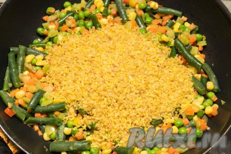 В сковороду с мексиканской смесью, обжарившейся в течение 5 минут, всыпать булгур (предварительно промывать его не нужно), перемешать. 