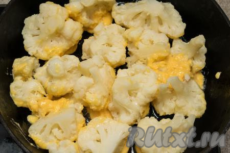 Жарить цветную капусту в кляре с сыром на среднем огне в течение 3-5 минут (до приятного подрумянивания кляра). Затем перевернуть соцветия, накрыть сковороду крышкой и жарить на небольшом огне ориентировочно ещё 3 минуты (на поверхности капусты не должно остаться влажных участков кляра), выключить огонь и дать капусте пропариться под крышкой 5 минут.