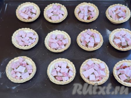 Колбасу нарезать на мелкие кубики, равномерно разложить по тарталеткам.&nbsp;