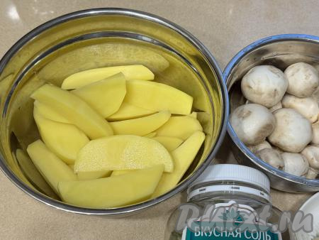 У меня были некрупные шампиньоны, я их готовила целиком. Крупные грибы нужно будет разрезать на 2-3 части. Картошку нарезать на средние дольки, как для картофеля по-деревенски. Сложить нарезанный картофель в глубокую миску.