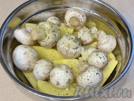 Выложить грибы к картошке, всыпать соль и специи по вкусу, влить растительное масло, добавить пропущенный через пресс чеснок.