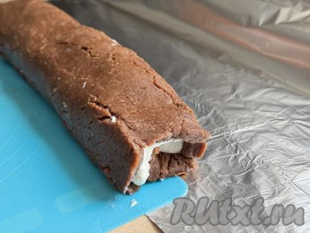 При помощи силиконового коврика (или пищевой плёнки) свернуть пласт с творожной начинкой и бананом в рулет, начиная сворачивать с более широкой стороны пласта. Переложить рулет на лист фольги. Плотно завернуть&nbsp;рулет из печенья и банана в фольгу, как конфету, и отправить в холодильник&nbsp;для стабилизации на ночь.&nbsp;