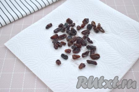 Изюм перебираем, удаляя, если есть, остатки веточек. Перекладываем изюм в небольшую миску, заливаем кипящей водой, оставляем минут на 5. Затем откидываем изюм на сито. Промываем изюм проточной водой, даём стечь лишней воде. Раскладываем изюм на бумажных полотенцах и оставляем его на несколько минут обсохнуть.