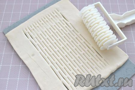 Выкладываем на присыпанную мукой поверхность второй пласт теста, тоже раскатываем его скалкой в квадрат со стороной 25 сантиметров. На поверхности теста делаем надрезы. Можно сделать несколько надрезов ножом, я сделала надрезы на тесте с помощью специального валика.