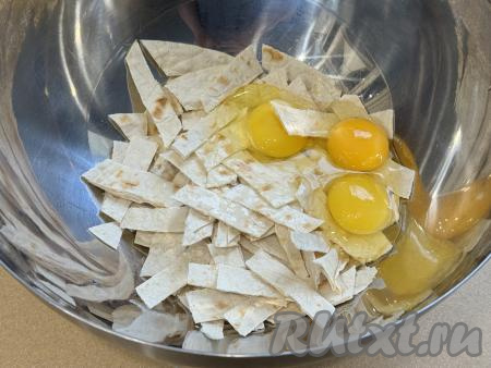 В глубокую миску нарезать на небольшие полоски лаваш, добавить сырые яйца, влить молоко.