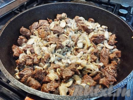 К говядине, протушившейся до мягкости, добавляем жареные шампиньоны с луком, перемешиваем и готовим под крышкой 5 минут, иногда помешивая.