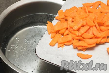 Влить в кастрюлю 2 литра воды, поставить на сильный огонь. Довести воду до кипения. Пока вода закипает нужно очистить морковку и картошку. Пока закипает вода, чтобы картофель не потемнел, можно его выложить в небольшую ёмкость и полностью залить водой. Нарезать морковь на достаточно тонкие брусочки (или полукружочки). В кастрюлю с закипевшей водой добавить нарезанную морковку.