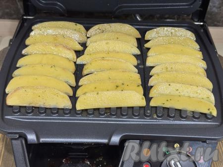Электрогриль разогреть. Готовить картошку по-деревенски будем на режиме электрогриля № 1 "Овощи". Смазать створки электрогриля растительным маслом, разложить дольки картофеля на нижнюю створку электрогриля в один слой.