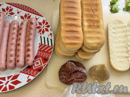 Листья салата вымыть. Крупные листья салата можно порвать на несколько частей. Огурцы нарезать на тонкие кружочки. Для того чтобы кетчуп и горчицу в дальнейшем было удобно наносить на хот-доги тонкими полосками, я в один целлофановый пакет выложила кетчуп, а в другой целлофановый пакет - горчицу. В углу каждого пакета сделала небольшой надрез.