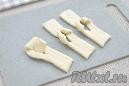 Для формирования хвороста берём один конец полоски и просовываем его через отверстие в центре, выворачивая на прежнее место. Постепенно формируем заготовки хвороста из всех полосок из слоёного теста.