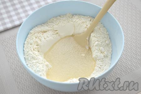 Получившуюся смесь солёной воды и масла вливаем в центр мучной смеси. Начинаем перемешивать ингредиенты лопаткой (или столовой ложкой).