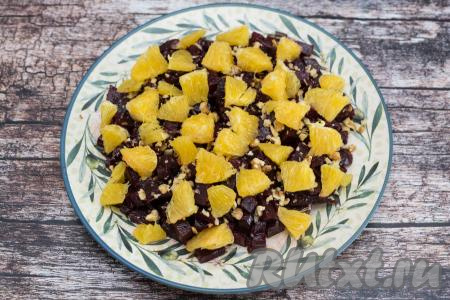 Выложить апельсин поверх свеклы с грецкими орехами и сразу подать салат к столу.