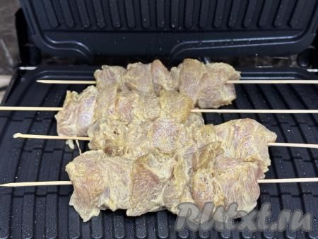 Электрогриль разогреть на режиме № 3 "Мясо", смазать створки электрогриля растительным маслом и выложить шпажки с куриным шашлыком.