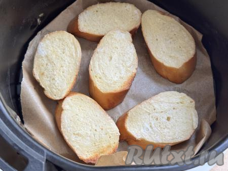 По прошествии 6 минут достать чашу из аэрогриля, перевернуть гренки из белого хлеба, снова отправить в аэрогриль, установить время - 4 минуты. Готовить до звукового сигнала, означающего окончание времени запекания. Готовые гренки переложить из чаши аэрогриля на тарелку. Так как все гренки сразу не помещаются в аэрогриль, то, вынув первую партию, можно сразу приступать к приготовлению оставшихся гренок.