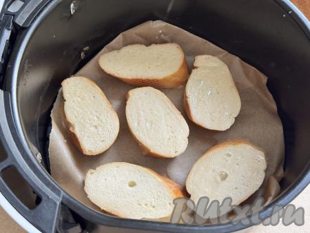 Чашу аэрогриля застелить пергаментом, выложить в один слой кусочки белого хлеба, покрытые яично-молочной смесью.