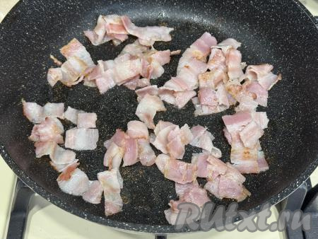 В сковороду влить немного растительного масла, выложить кусочки бекона. Обжарить бекон на среднем огне 5 минут, иногда помешивая.