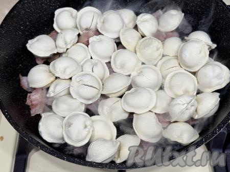 Затем добавить в сковороду замороженные пельмени, перемешать.