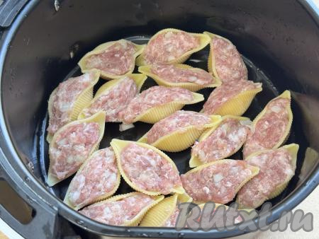 Из чаши аэрогриля убрать решётку, выложить макароны "Ракушки", наполненные фаршем, в один слой.&nbsp;
