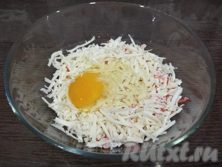 Разбиваем сырое яйцо к сыру и палочкам.