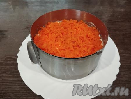 Следующим слоем выкладываем варёную морковь, натёртую на крупной тёрке.