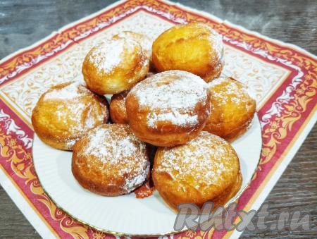 Выкладываем пончики на тарелку и посыпаем сахарной пудрой.