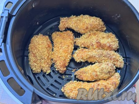 Выставить температуру аэрогриля 180 градусов, время - 20 минут. Запекать куриные стрипсы в аэрогриле до золотистого цвета. После звукового сигнала аэрогриля, сообщающего об окончании времни запения, нужно проверить готовность стрипсов, разрезав одну полоску, если мясо в разрезе светлое, без кровяных вкраплений, значит оно готово.