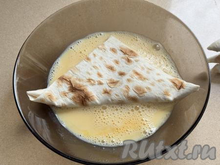 По очереди окунуть во взбитое яйцо с двух сторон столько треугольников из лаваша, сколько вы одновременно сможете пожарить на сковороде. Я жарила на сковороде одновременно по 2 треугольника, поэтому именно столько треугольников из лаваша и покрывала яичной смесью с двух сторон.