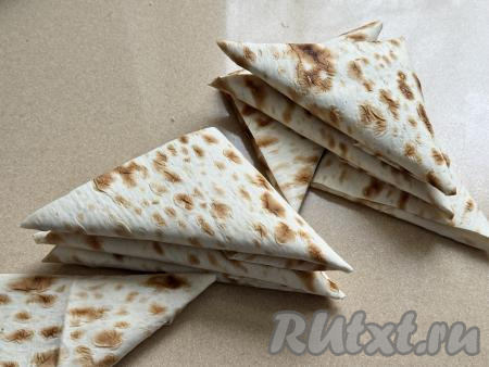 В результате сворачивания получится аккуратный треугольный конвертик из лаваша. Таким образом сформировать&nbsp;8 треугольников из лаваша с начинкой из крабовых палочек и сыра.