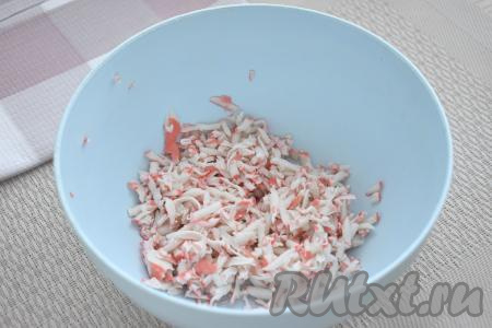 Яйцо отвариваем в течение 10 минут с момента закипания воды, даём остыть, очищаем. Крабовые палочки, если они заморожены, полностью размораживаем при комнатной температуре. Затем достаём крабовые палочки&nbsp;из упаковки и натираем их&nbsp;на крупной тёрке в глубокую миску.