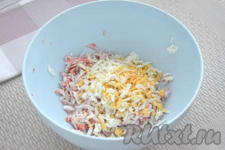 Варёное яйцо тоже натираем на крупной тёрке, добавляем в миску с крабовыми палочками.