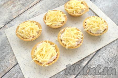 Начинку в тарталетках посыпаем сыром твёрдых сортов, натёртым на крупной тёрке.
